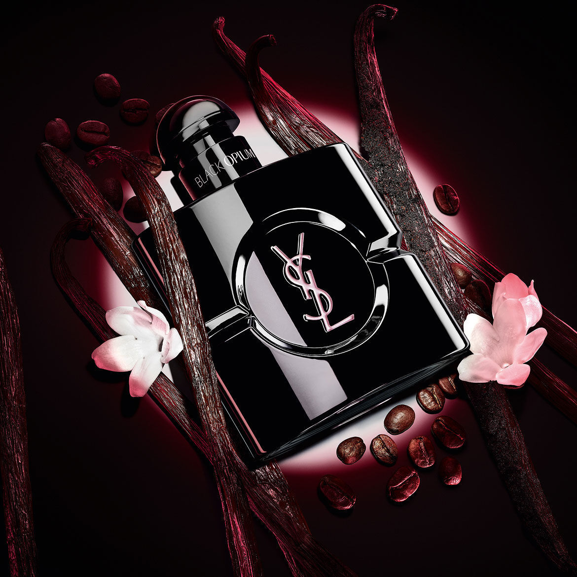 Black Opium Le Parfum bottle in glossy black, surrounded by dark vanilla pods and white jasmine.