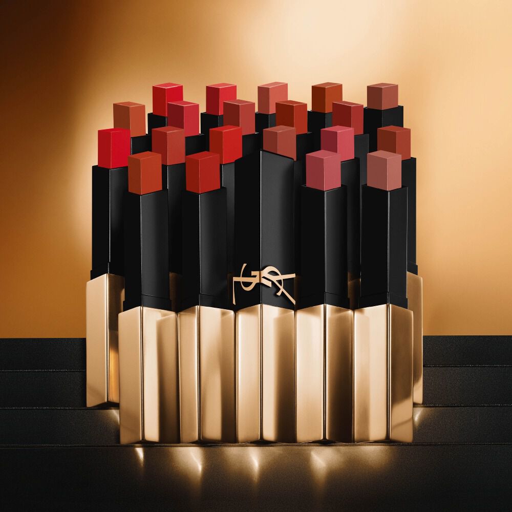 Multiple Yves Saint Laurent slim square lipsticks in various shades of red and nude on a golden background.