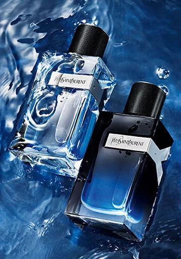 Two stylish perfume bottles resting on a shimmering blue water surface, one clear and the other dark, both showcasing a modern design.