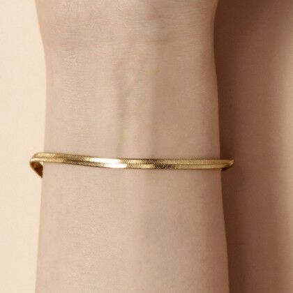 A close-up of a slender gold bangle worn on a wrist.