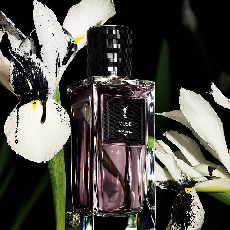 A rectangular perfume bottle labeled "MUSE INSPIRING INK" by YSL, surrounded by elegant white and black irises.