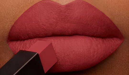 Close-up of a pair of full lips being applied with red lipstick.