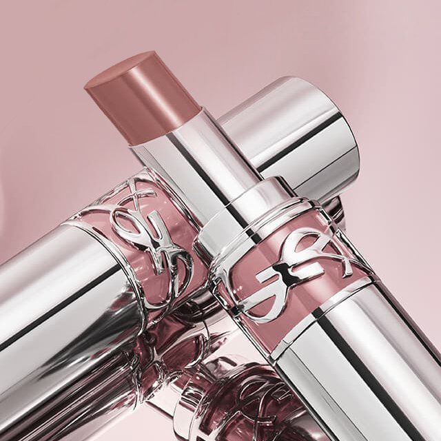 Two YSL lipsticks in silver and pink, one open showing a nude shade.