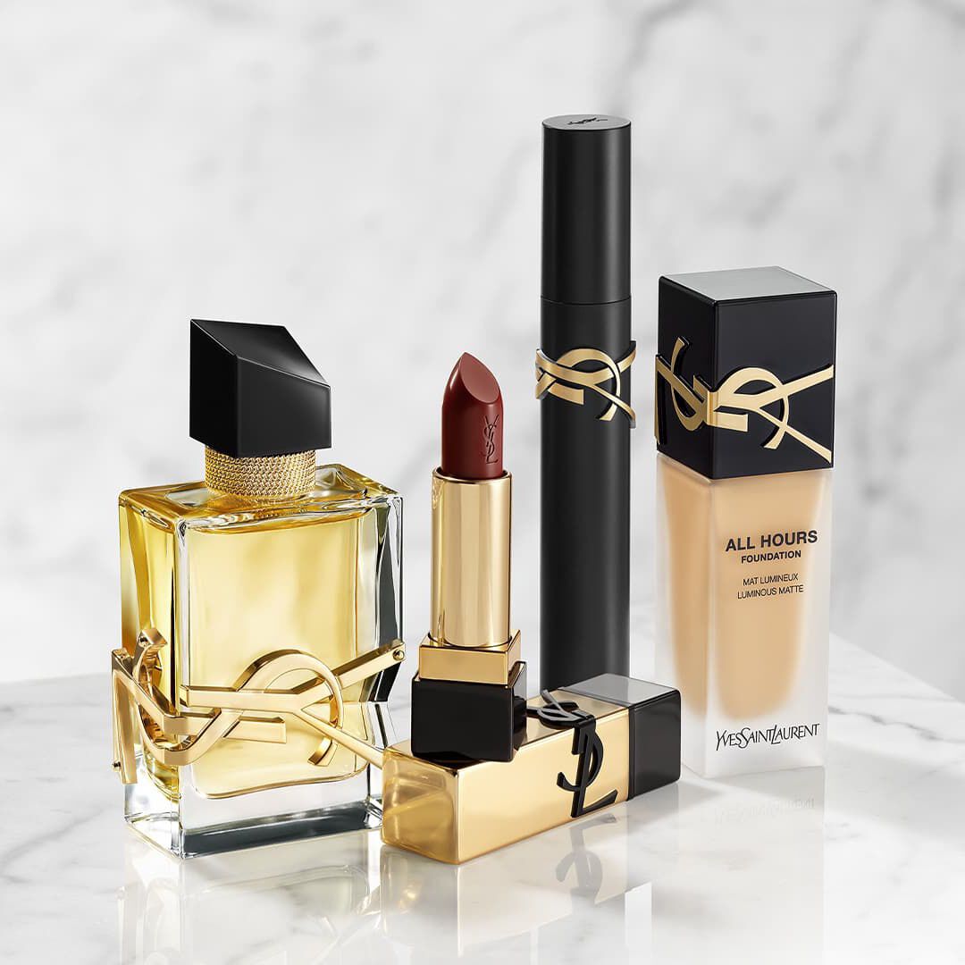 YSL beauty products: perfume, lipstick, mascara, and foundation on marble.