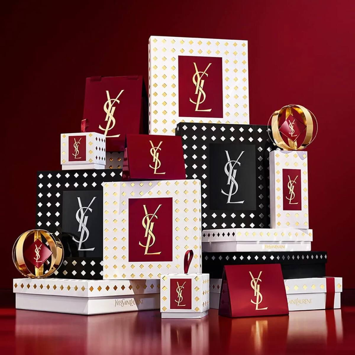 Yves Saint Laurent holiday collection gift sets and luxury beauty products displayed against a festive red background.