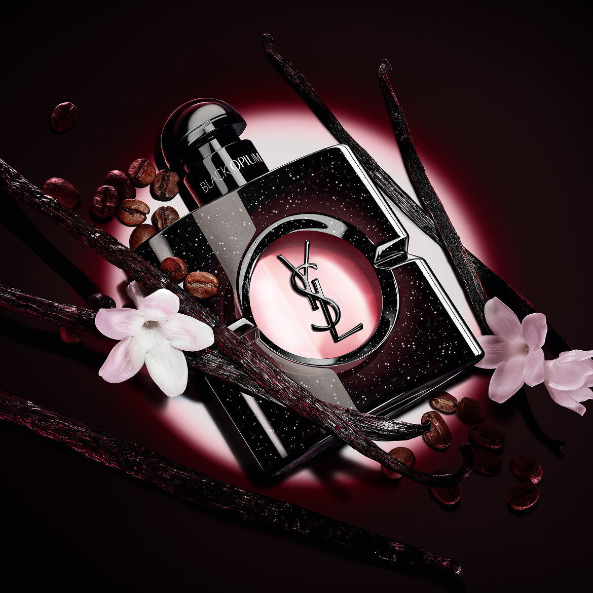 Black Opium Eau de Parfum bottle with white jasmine flowers, vanilla pods, and roasted coffee beans.