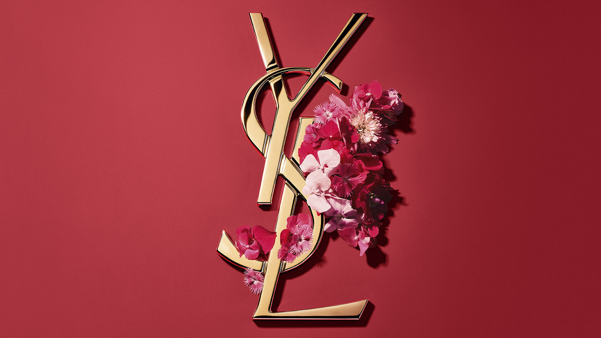 Red YSL gift box with pink flowers on a red background.​
