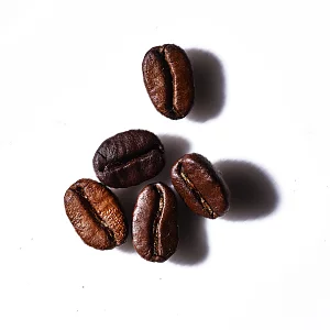 Five roasted coffee beans scattered on a white background.