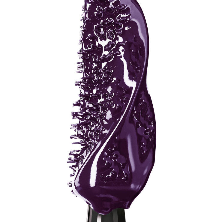 Extreme close-up of a mascara wand heavily coated in a creamy, glossy deep purple formula.