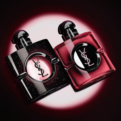 Two Yves Saint Laurent Black Opium perfume bottles illuminated on a dark background.