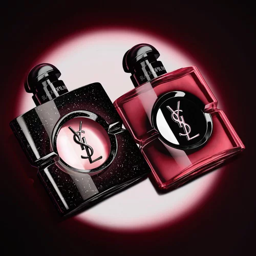 Two Yves Saint Laurent Black Opium perfume bottles illuminated on a dark background.