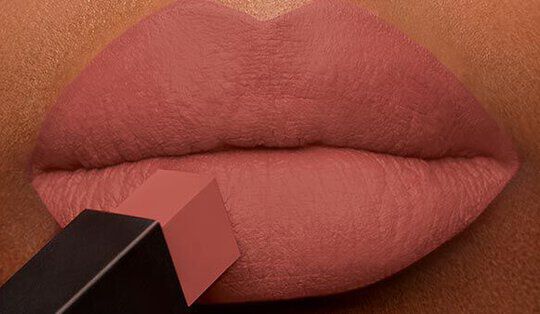 Close-up of soft, fuller lips being coated with a creamy nude lipstick.