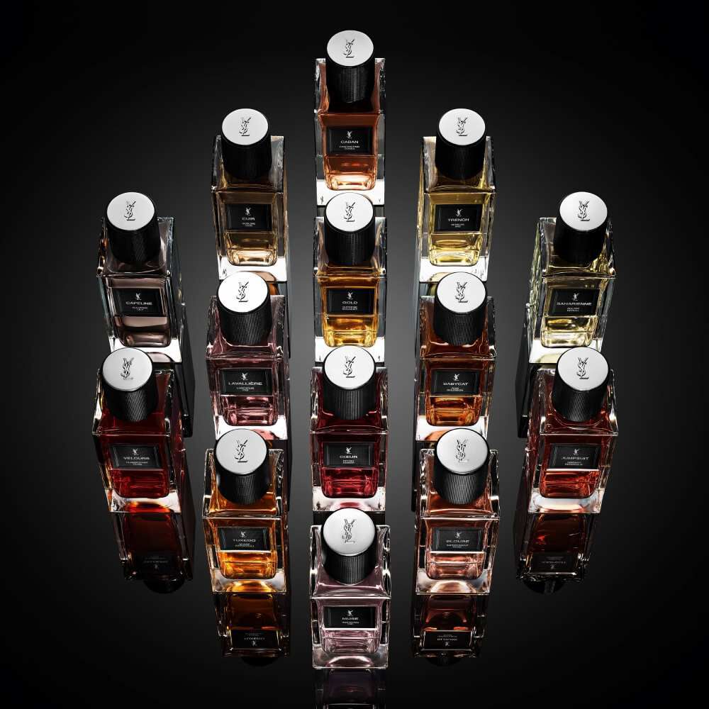 YSL fragrance bottles arranged in a geometric display on black background.