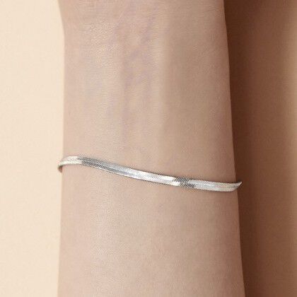A slender silver bracelet resting on a person's wrist with a smooth, polished surface.