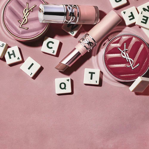 YSL makeup products and letter tiles on a pink background.