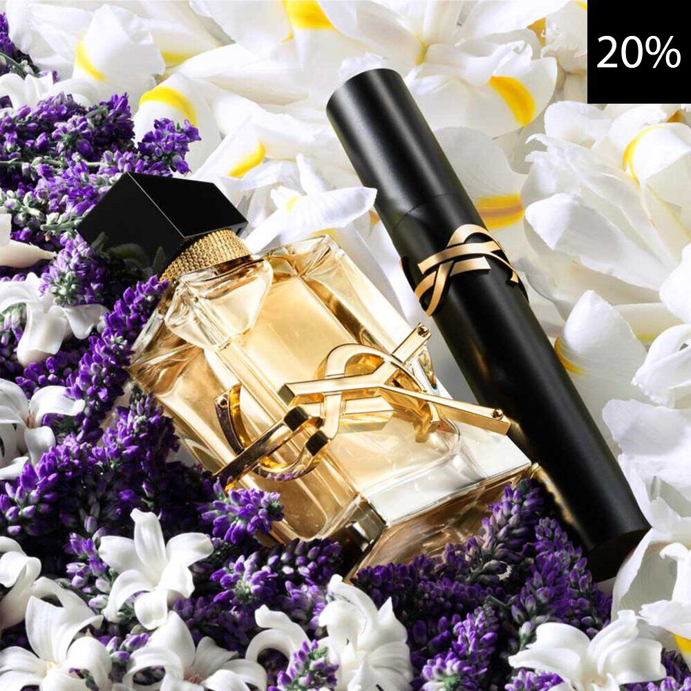 A close-up of an elegant YSL Libre perfume bottle and a black YSL mascara, both with gold accents, nestled among vibrant purple lavender and delicate white and yellow flowers. A black square with white text '20%' is visible in the top right corner, indicating a discount.