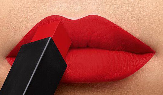 Close-up of vibrant red lips with a red lipstick bullet being applied.