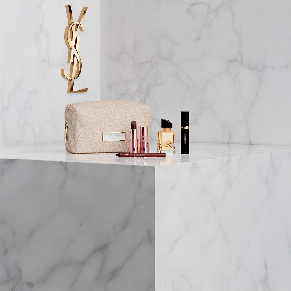 YSL Beauty pouch with lipstick, eyeliner, perfume, and mascara on a marble shelf.