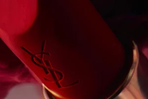 A close-up of a YSL lipstick in a striking red shade, with a blurred background that enhances its vibrant color.