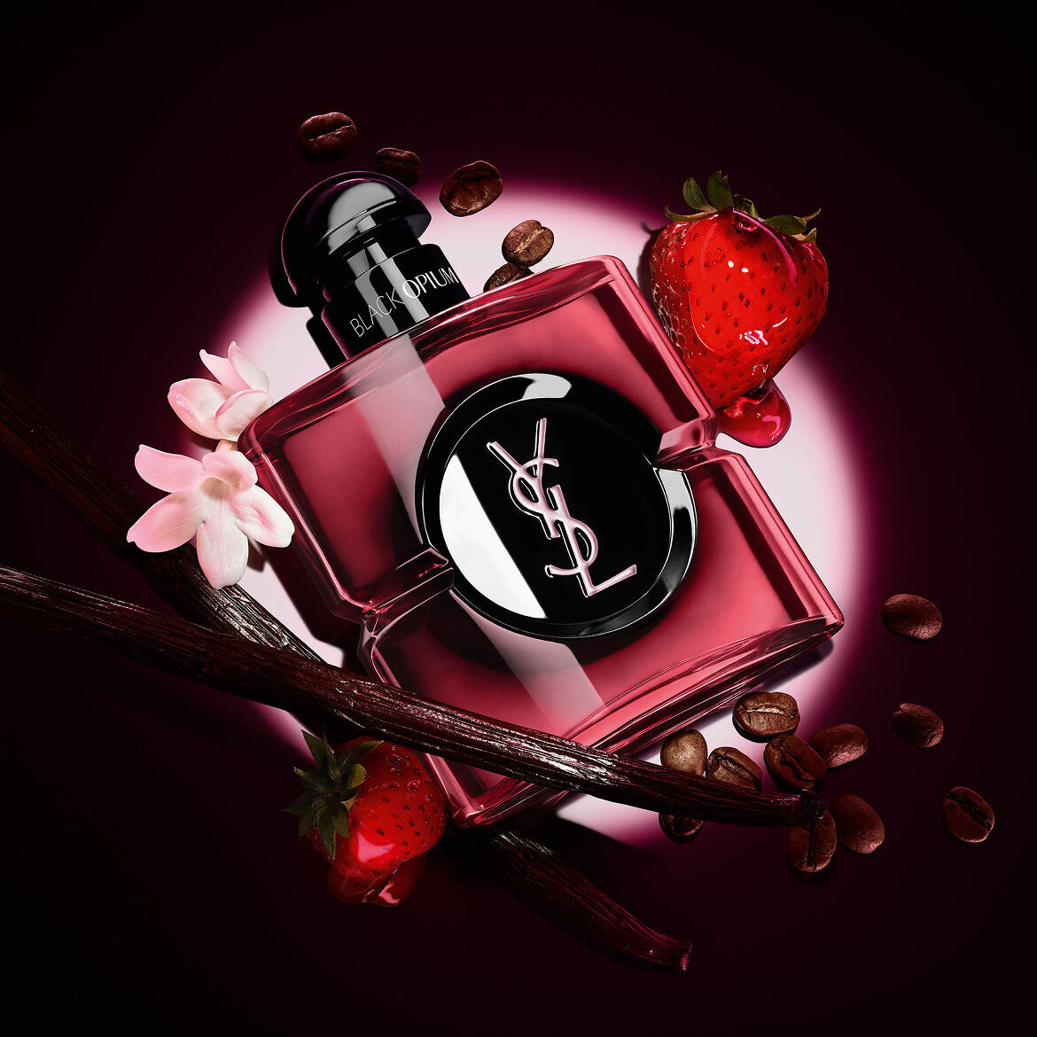 Black Opium Eau de Parfum Pink Glaze bottle surrounded by fresh strawberries, vanilla pods, coffee beans, and jasmine.