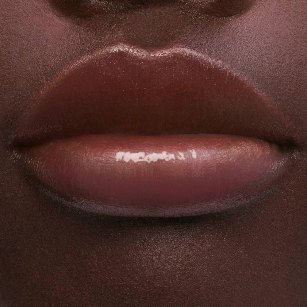 Close-up of full, smooth lips with a natural sheen on a dark skin tone.