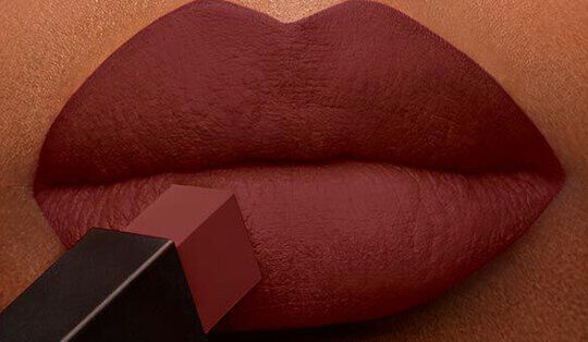 Close-up of a pair of lips being colored with a dark brown lipstick.