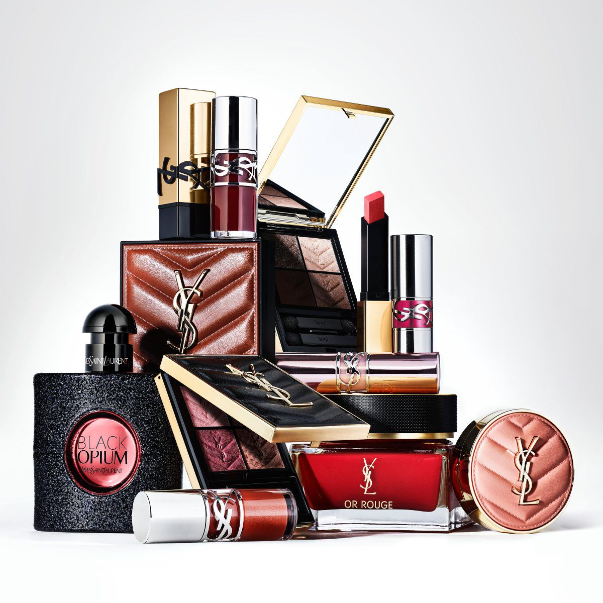 An Yves Saint Laurent Libre perfume bottle and its refill stand on a marble surface against a marbled background.