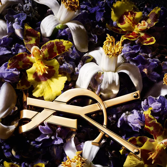 A close-up of a gold decorative piece nestled among a vibrant display of purple and yellow flowers.