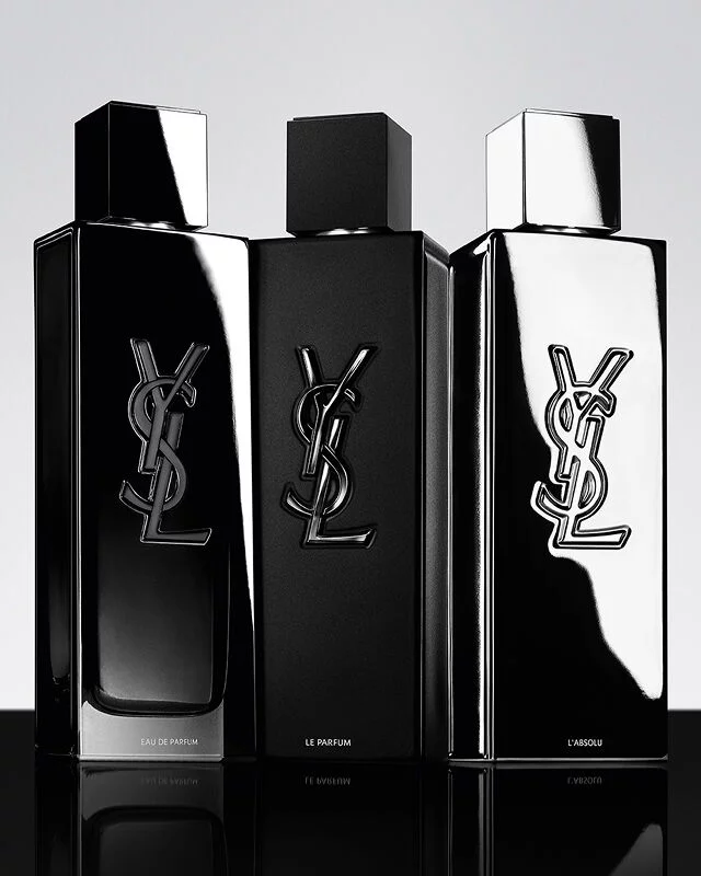Three YSL Y men's perfumes: Eau de Parfum, Le Parfum, and L'Absolu, displayed in their distinct black and silver bottles.
