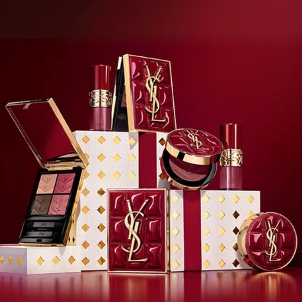 Yves Saint Laurent holiday collection gift sets and luxury beauty products displayed against a festive red background.