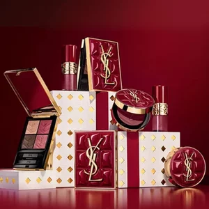 Yves Saint Laurent holiday collection gift sets and luxury beauty products displayed against a festive red background.
