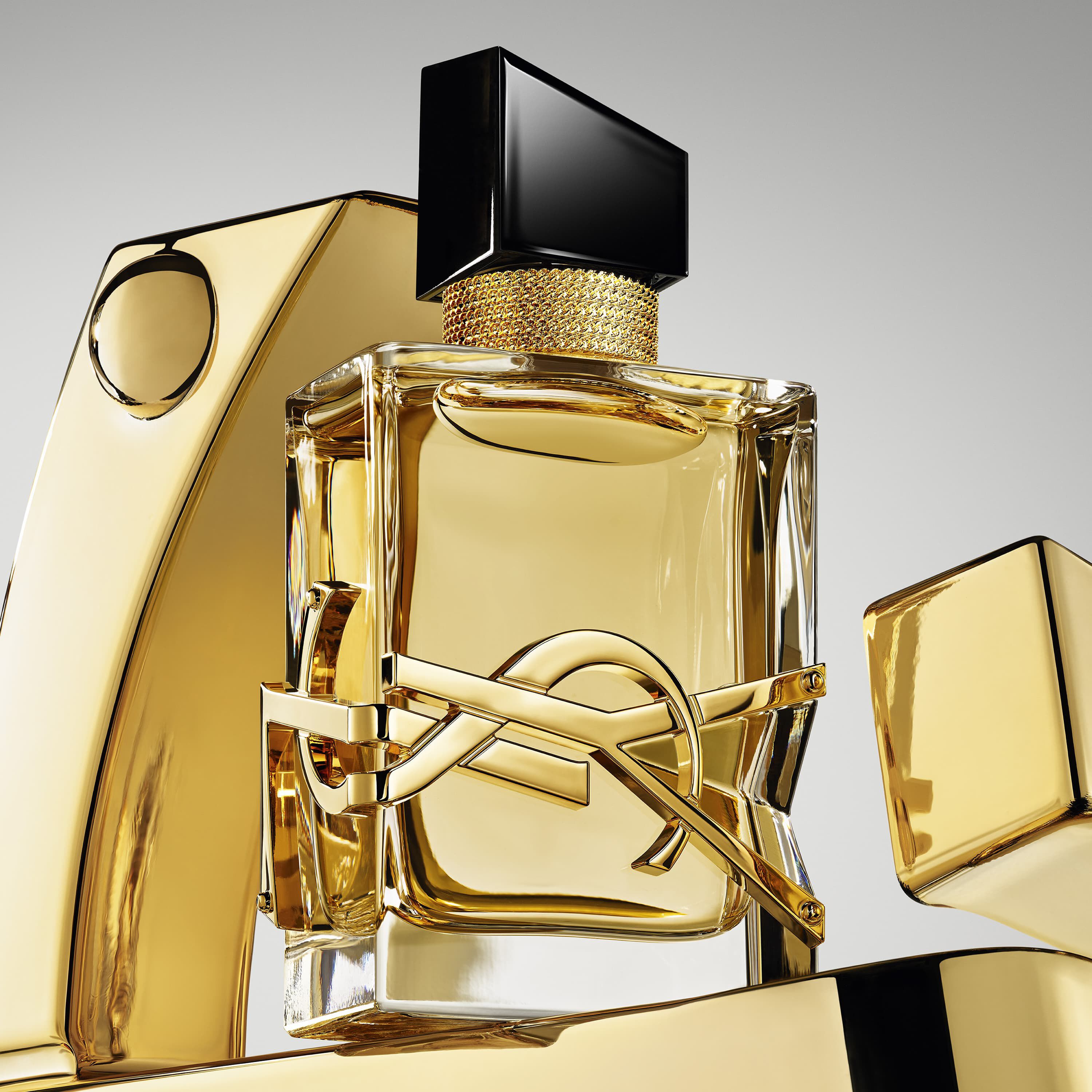 YSL perfume bottle, gold with black cap and logo, surrounded by golden elements.