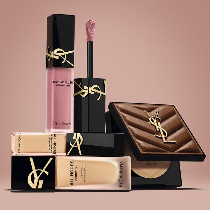 YSL beauty products including blush, foundation and compact powder on a nude background.