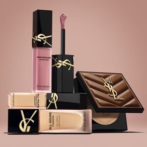 YSL beauty products including blush, foundation and compact powder on a nude background.