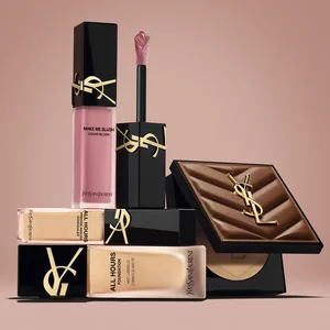 YSL beauty products including blush, foundation and compact powder on a nude background.
