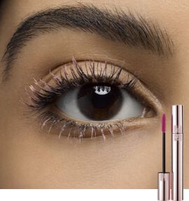 Close-up of an eye with long, defined lashes, featuring a tube of mascara and a pink lip product beside it.