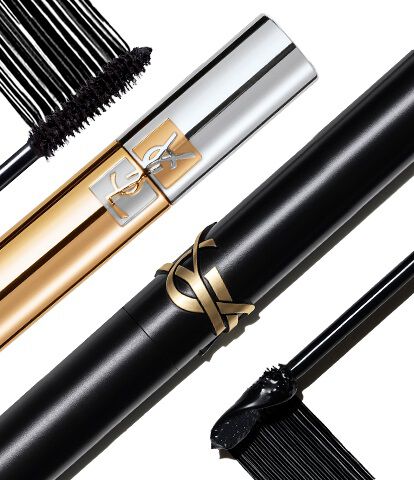 Three stylish mascara tubes are arranged diagonally, featuring sleek silver, gold, and black designs, with brushes partially exposed to showcase their unique styles.