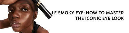 A close-up of a model showcasing a smoky eye makeup look, holding a makeup product above her eye, with text that reads "LE SMOKY EYE: HOW TO MASTER THE ICONIC EYE LOOK."