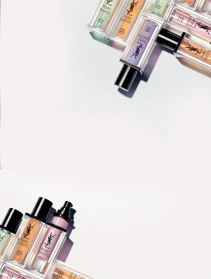 A flat lay of various YSL beauty fragrance bottles arranged with a clean, white background, showcasing an assortment of colors and designs.