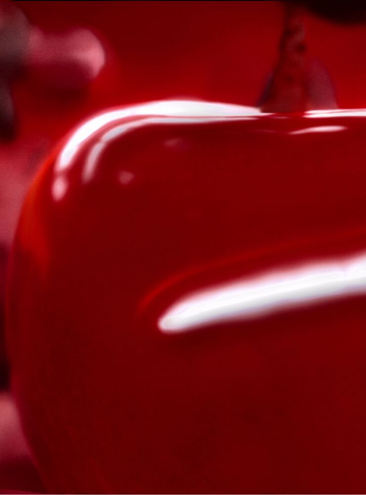 A close-up of a glossy red surface with soft reflections and contours, creating a smooth, vibrant appearance.