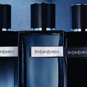 Three elegant bottles of Yves Saint Laurent perfume against a blue background.