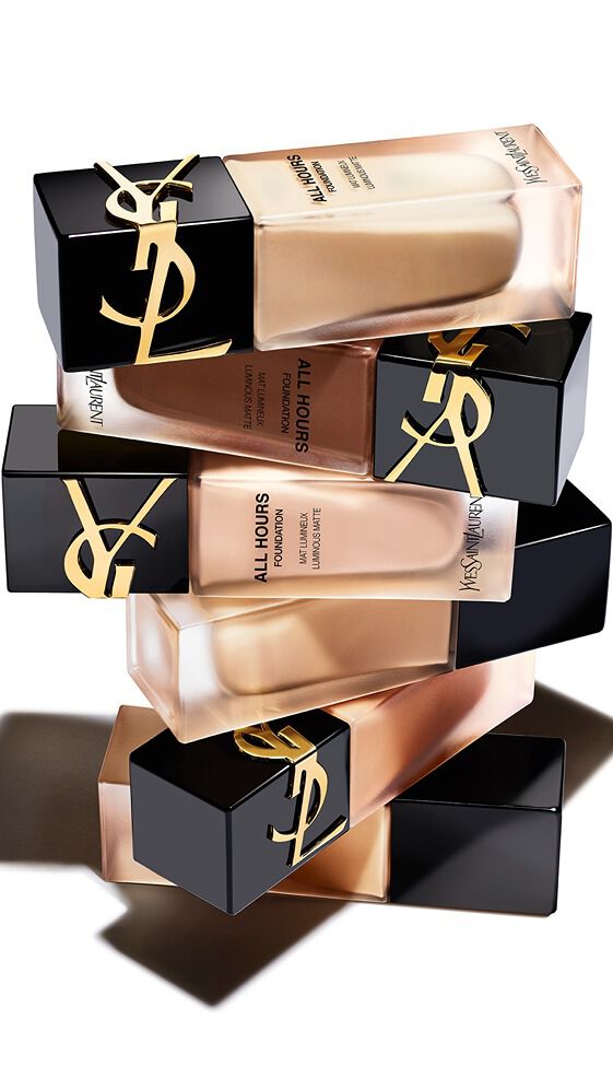A stack of YSL foundation bottles in various shades, featuring sleek black and gold packaging against a white background.