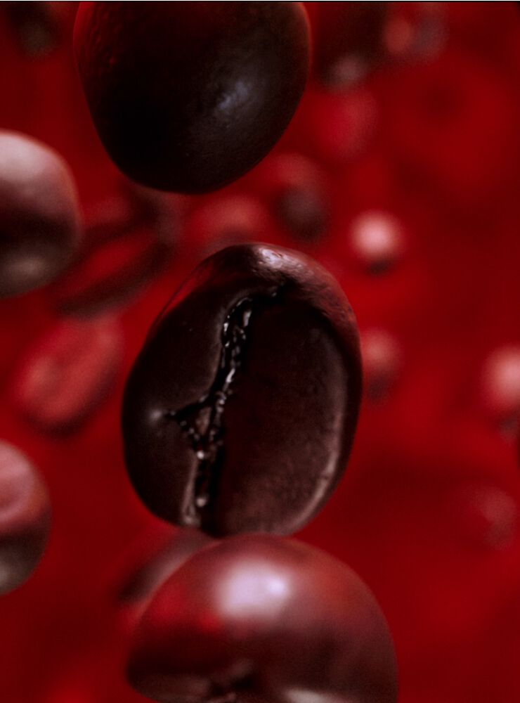 Close-up of a floating coffee bean against a blurred red background, highlighting its glossy surface and intricate texture.
