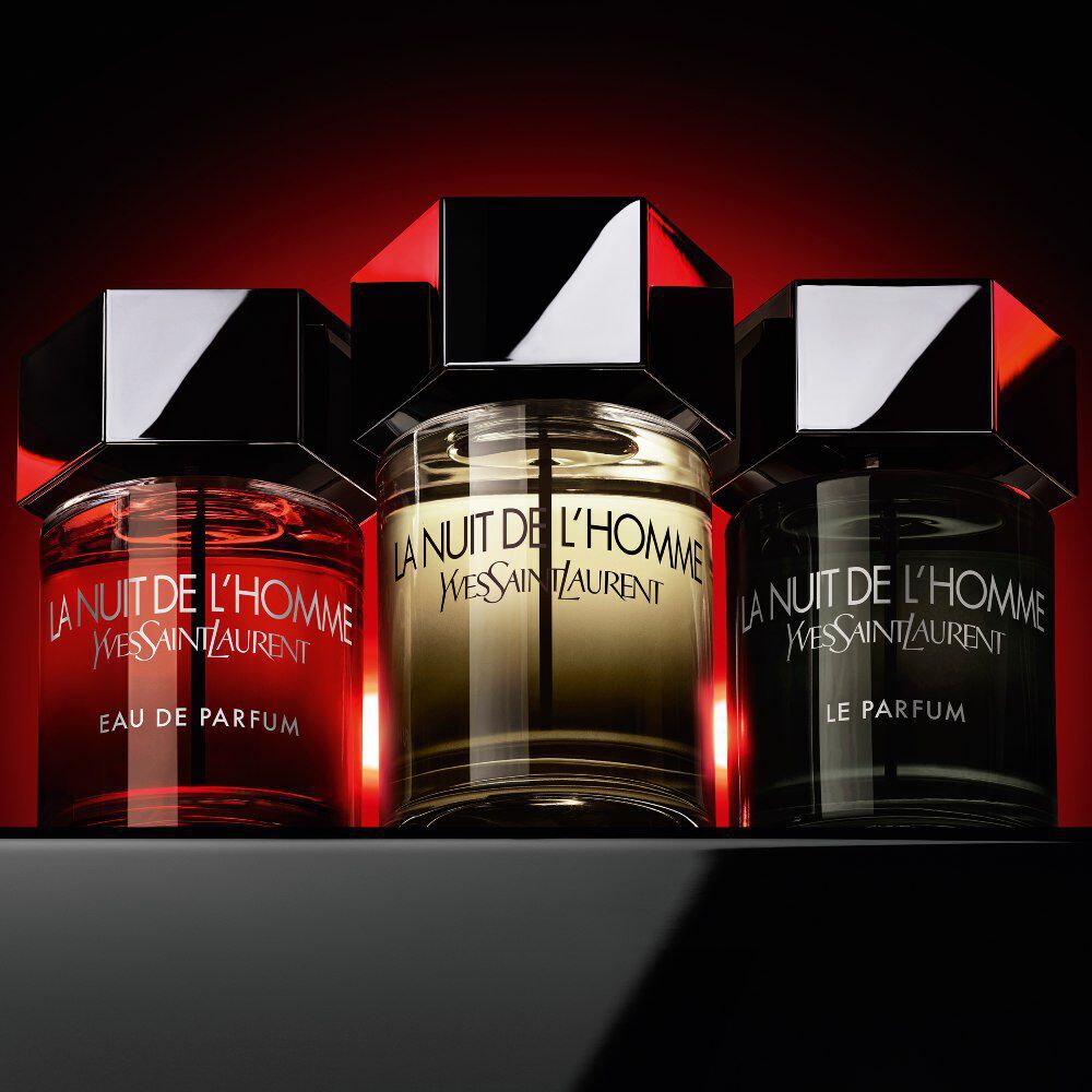 The La Nuit de l’Homme collection—Eau de Parfum, Eau de Toilette, and Le Parfum—displayed together against a dramatic red and black background.