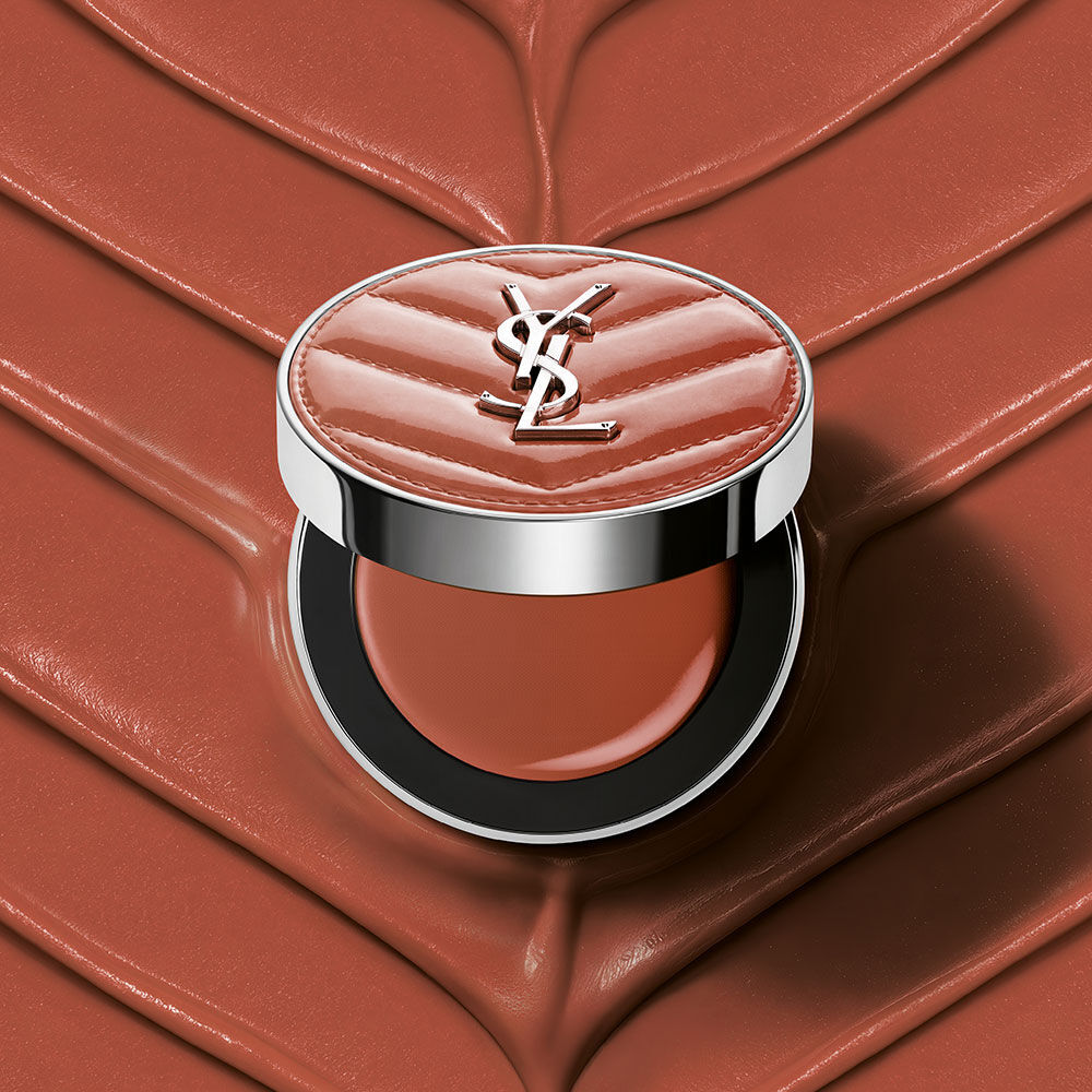 An open YSL Make Me Blush Lifted Glow Cream Blush compact in shade #44 Nude Lavalliere on a matching pink textured cream background.