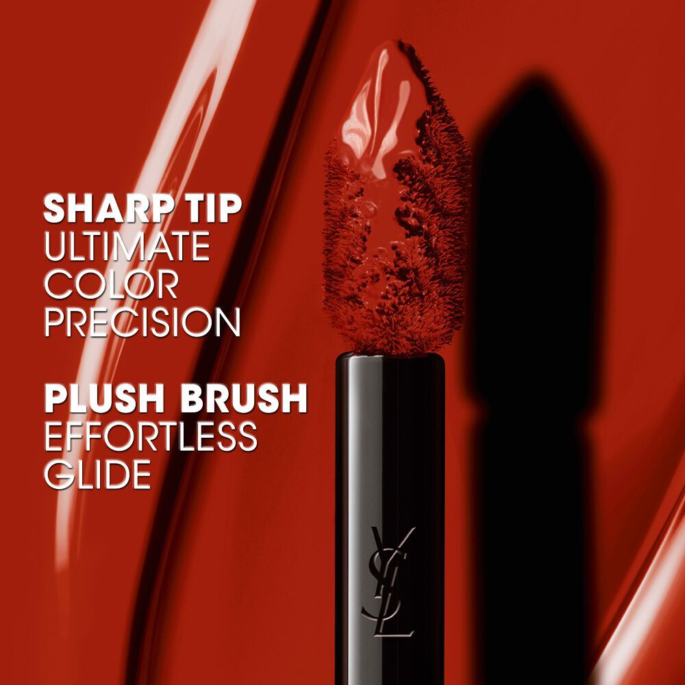 Close-up of a pointed YSL applicator brush coated in glossy red liquid lip stain. Text reads: "SHARP TIP ULTIMATE COLOR PRECISION" and "PLUSH BRUSH EFFORTLESS GLIDE."