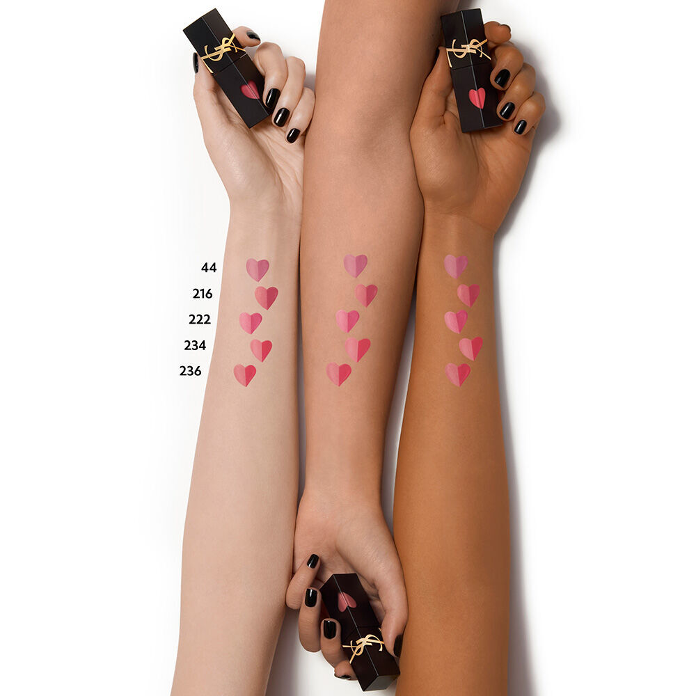 Heart-shaped lip stain swatches displayed on light, medium, and deep skin tone arms, with each hand holding a black YSL lip stain bottle with black manicured nails.