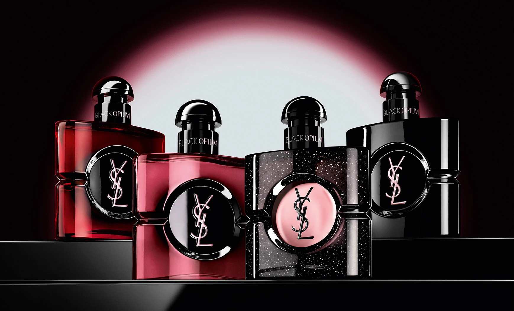 Four different Black Opium perfume bottles displayed in a row on a dark, reflective surface.