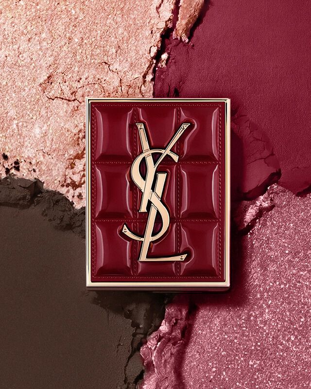 YSL Couture Mini Clutch palette set against a textured background of shimmering eyeshadow powders of #1982 Burgundy Millesime.