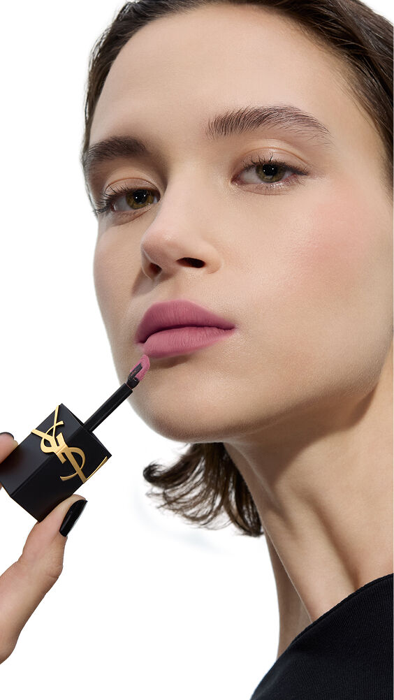 Fair skin tone model applying a cool-toned, soft-mauve shade of YSL THE INKS BLUR lip stain with the wand applicator.